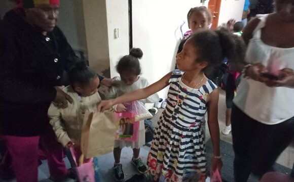 Children receiving wrapped holiday gifts at a partner centre in Belize