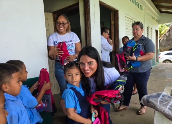 A Build Belize volunteer handing new backpacks to primary school pupils
