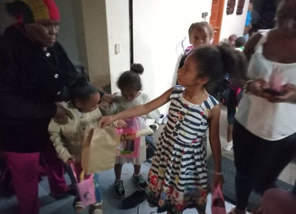 Children receiving wrapped holiday gifts at a partner centre in Belize