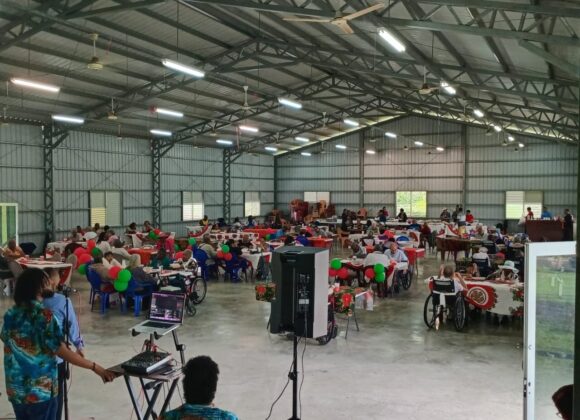 A large festive gathering of residents in a community hall