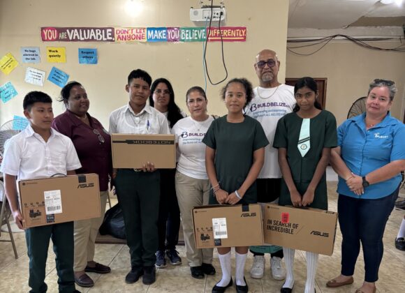 Students and Build Belize volunteers holding donated laptop boxes