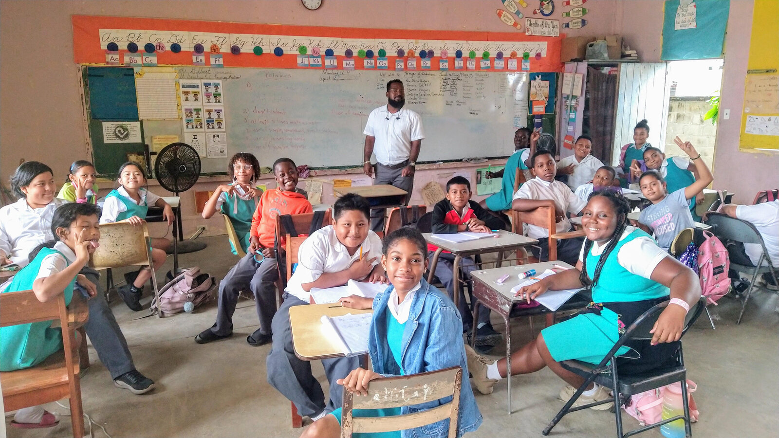A teacher with smiling pupils at their desks in a Belizean classroom